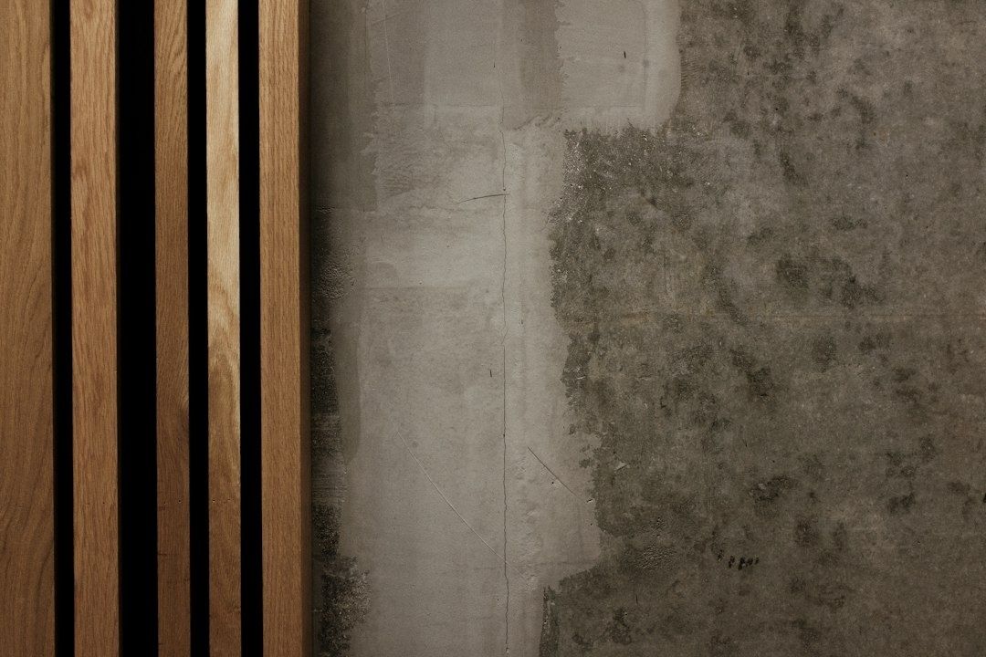 Vertical oak slats beside a textured gray concrete wall