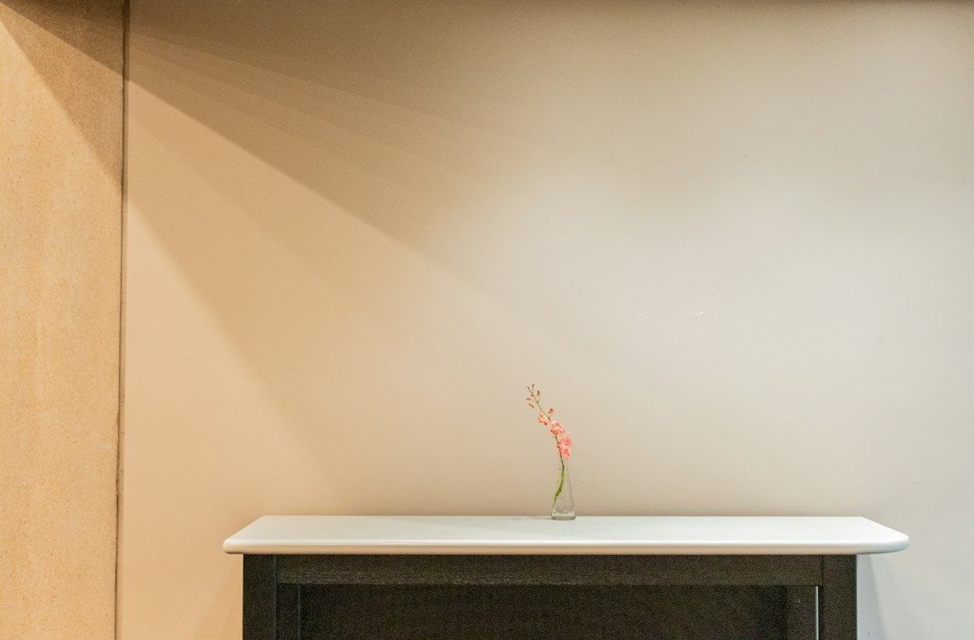 Minimalist console with a small flower vase against a plain wall